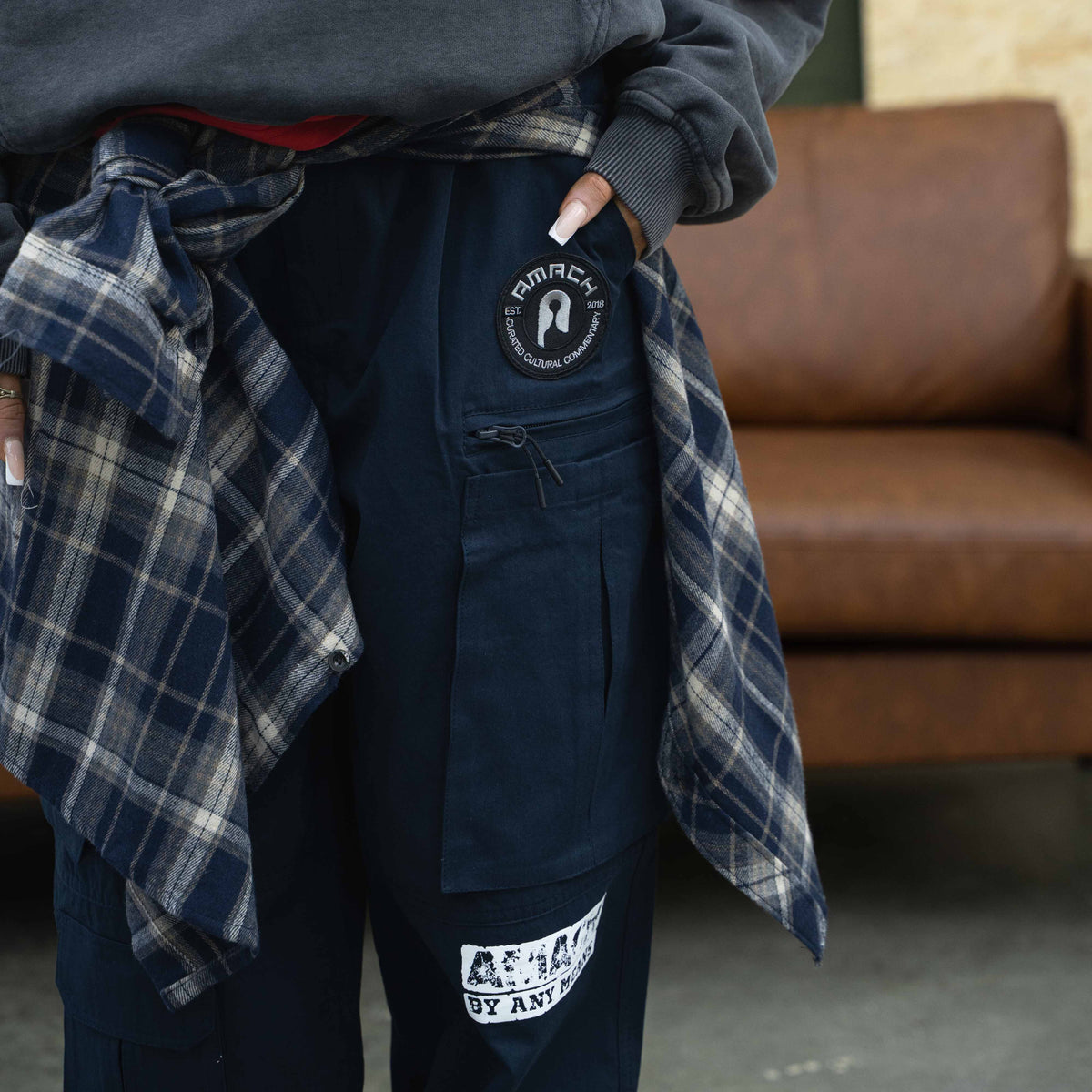 AMACH By Any Means navy cargo trousers with embroidered patches, worn with a plaid shirt