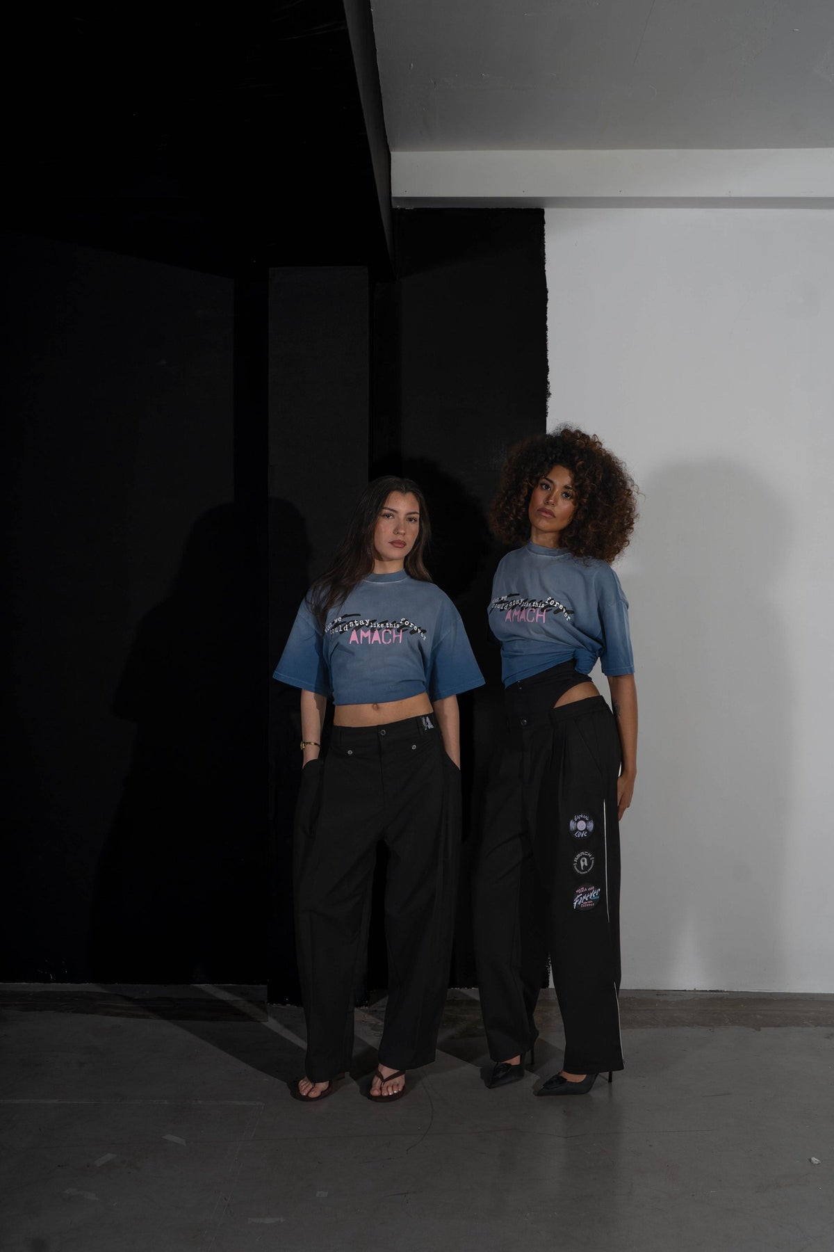 Two models in AMACH Stay Like This Forever t-shirts and black slacks