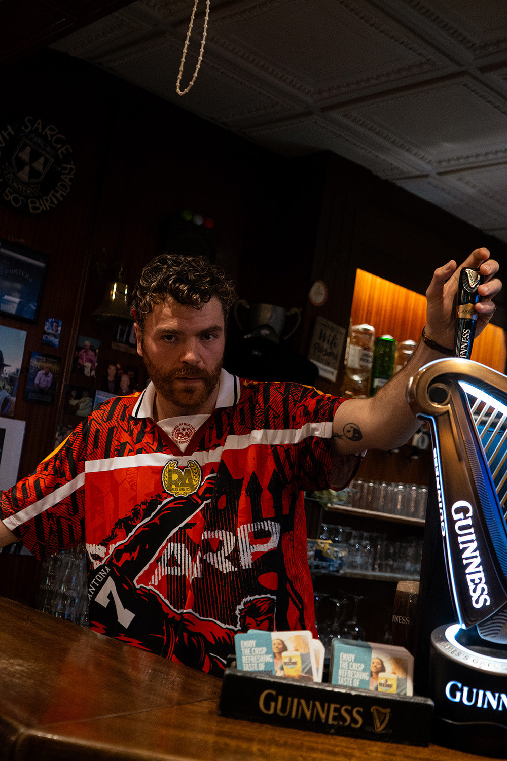 AMACH Rebel Athletics Cantona jersey worn behind the bar at Porters Bar, Derry