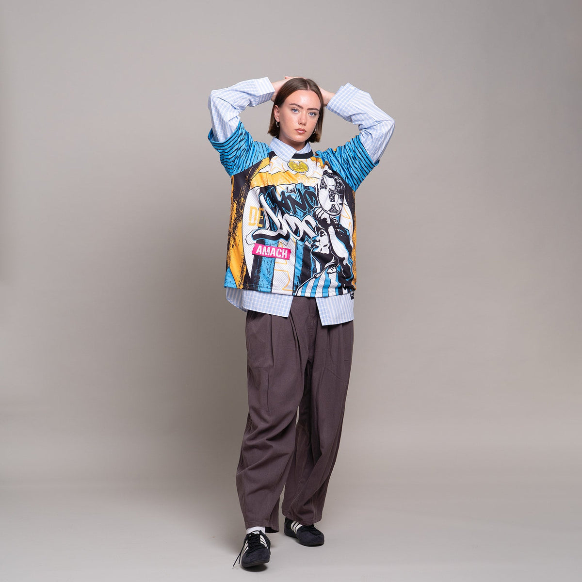 AMACH Rebel Athletics Maradona jersey worn with relaxed grey trousers