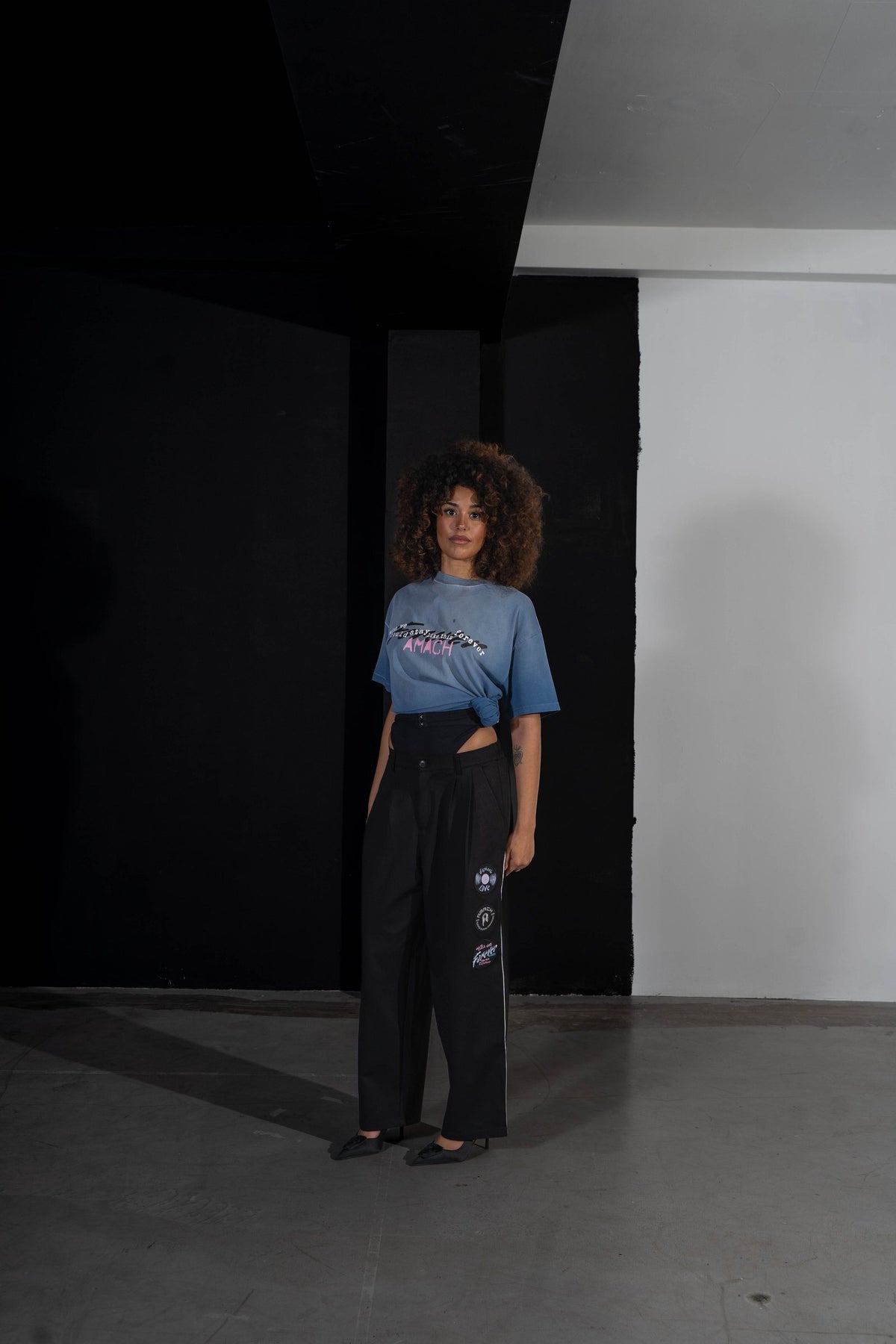 Model in the AMACH Stay Like This Forever t-shirt tucked into Euphoric Love slacks